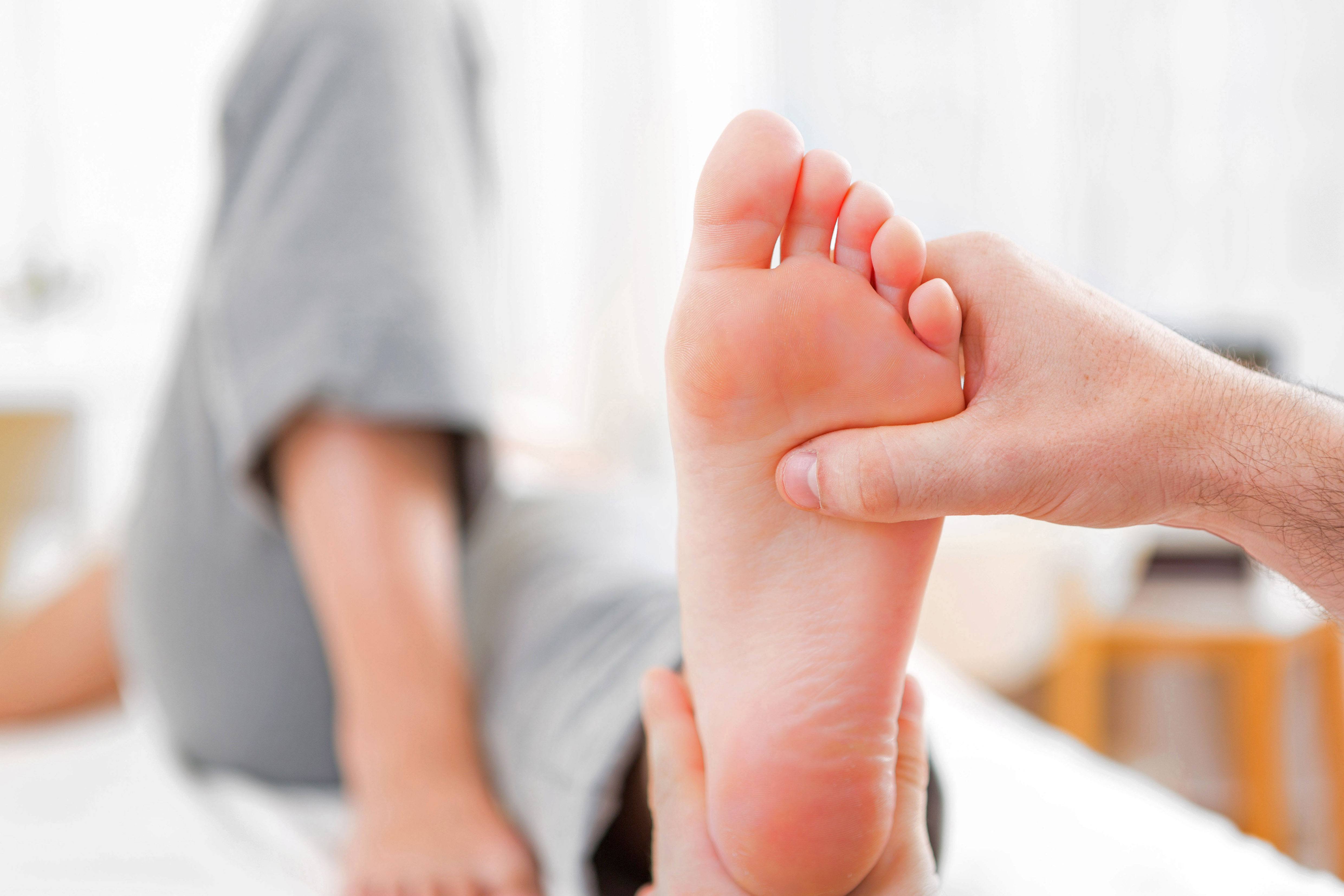 Arzt untersucht einen Fuß per Fingerdruck auf Nervenschäden