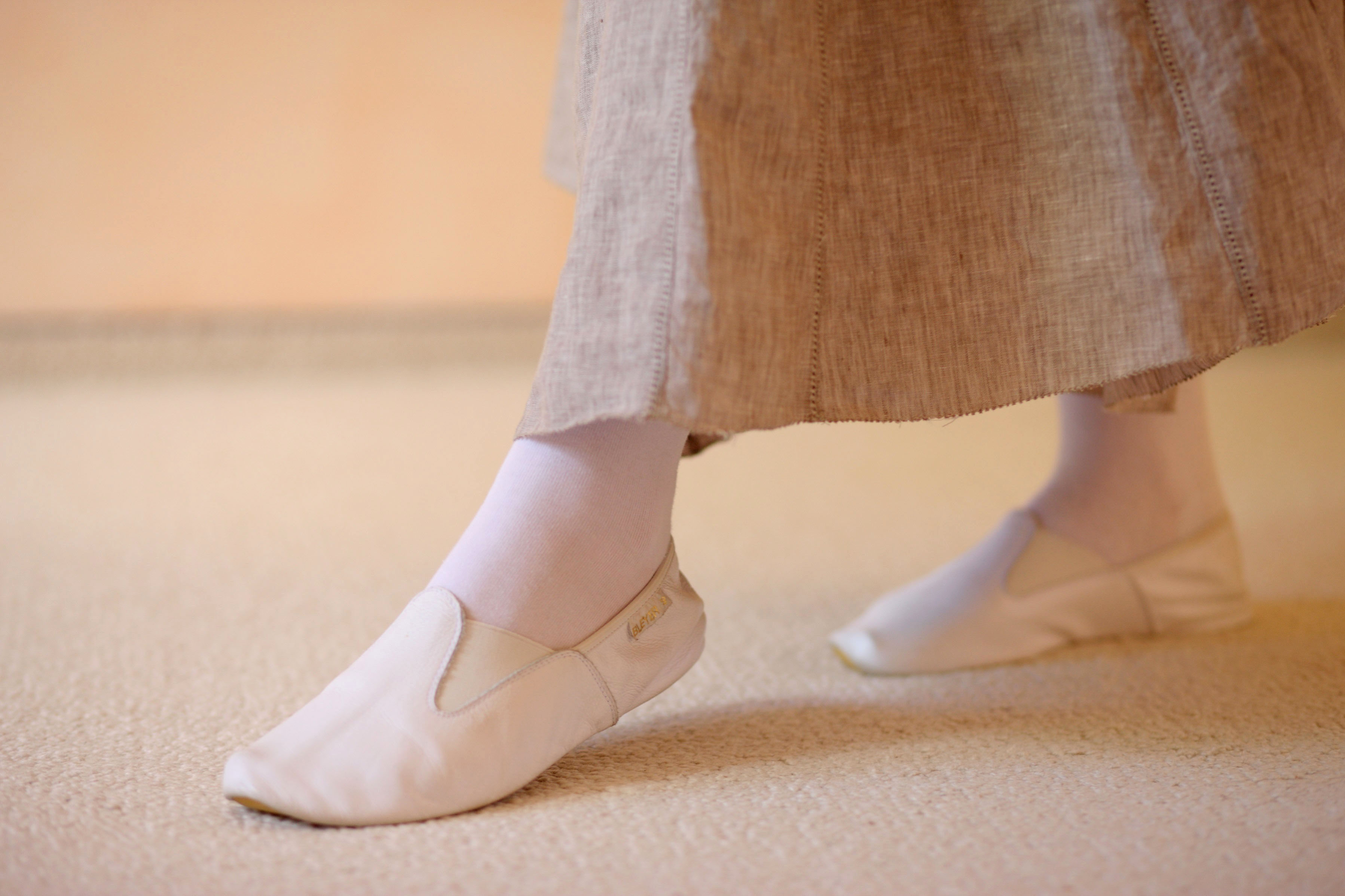 Ein Fuß in Gymnastikschuhen wird sanft vor den anderen aufgesetzt