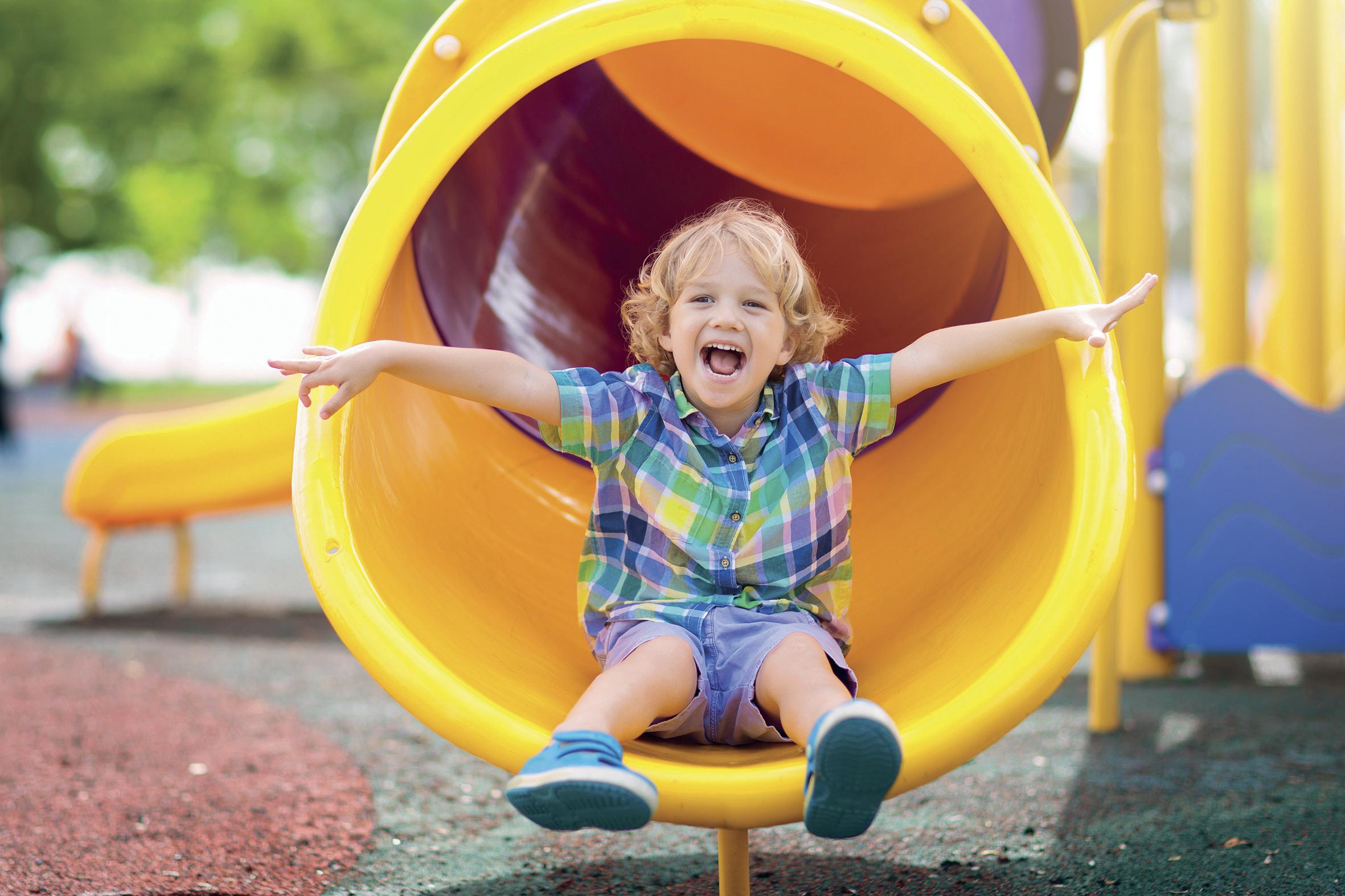 Kind rutsch durch eine Röhre auf dem Spielplatz