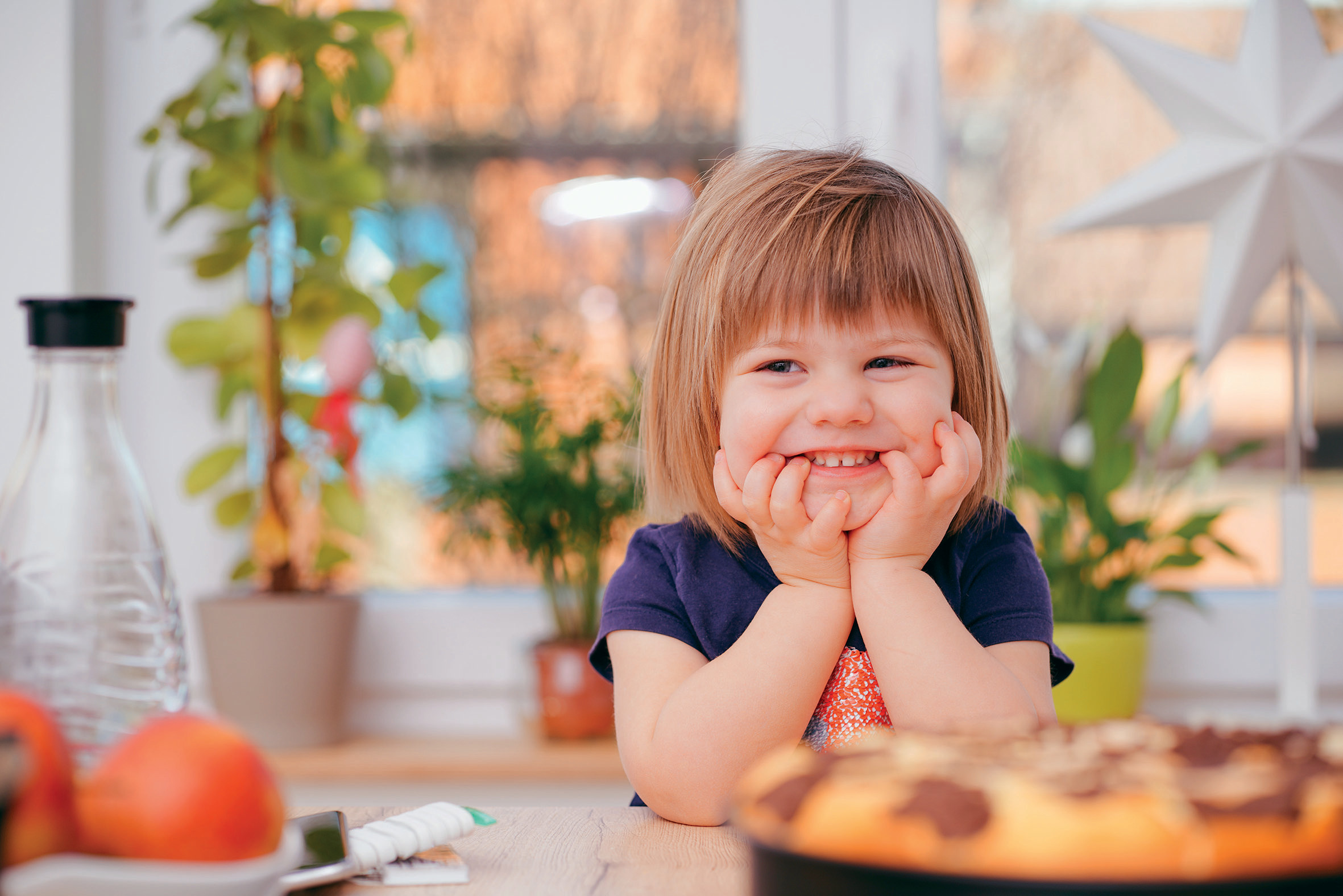 Fröhlich lachendes Kind sitzt am Küchentisch