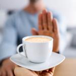Frau streckt Hand gegen Tasse Kaffee als Ablehnung zu trinken